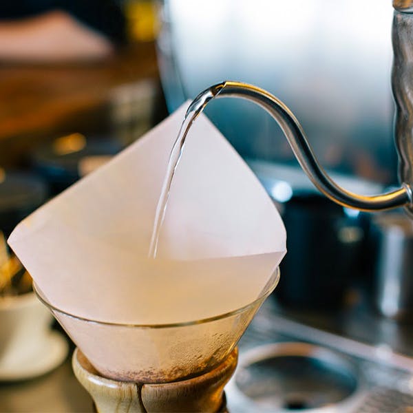 Un barista verse de l'eau dans une préparation en café filtre